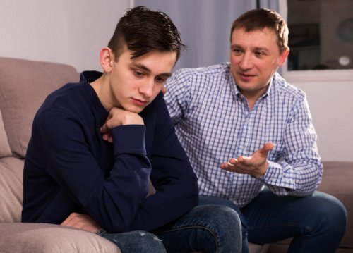 Padre intentando hablar con su hijo adolescente sobre sus derechos.
