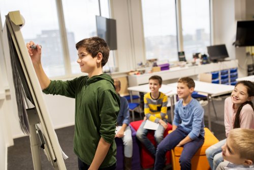 Alumno escribiendo en la pizarra para sus compañeros y trabajar los hábitos de la mente en el aula.