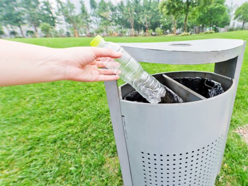 A person recycling a plastic bottle.