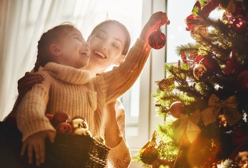 Madre e hija decorando el árbol de Navidad.