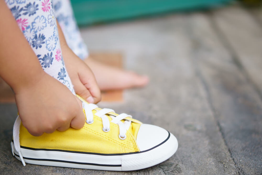 A girl tying her shoes.