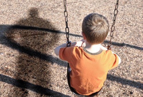 Enfant assis sur une balançoire.