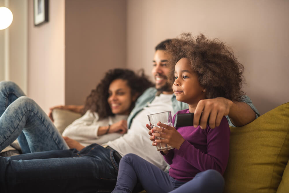 Padres viendo la televisión con su hija.