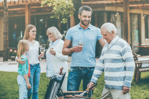 Familia pasando las vacaciones de verano en casa de los suegros y haciendo una barbacoa.