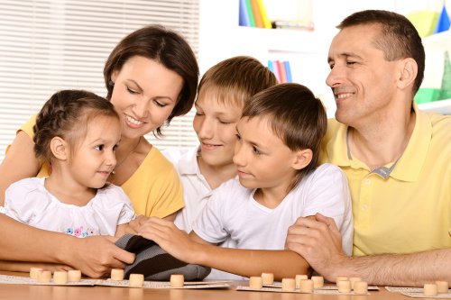 Padres con sus hijos jugando a juegos para mejorar la ortografía en familia.