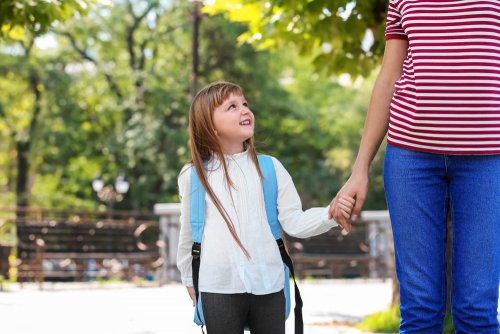 Niña yendo al colegio de la mano de su madre.