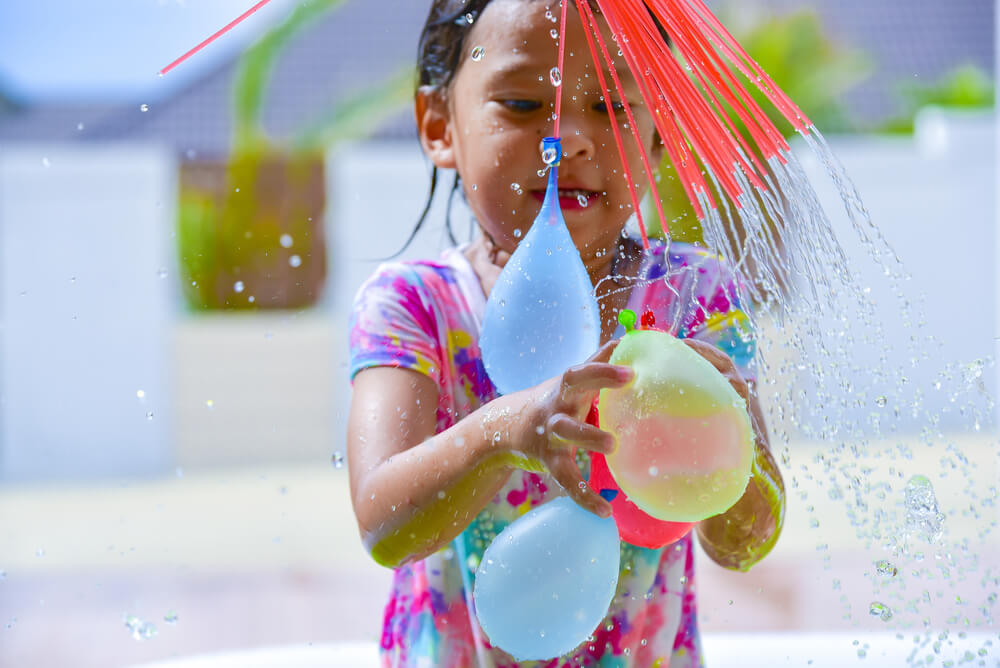 Bambina con palloncini d'acqua che prepara giochi per divertimento.