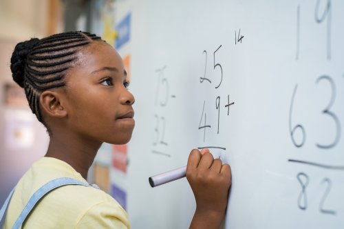 Une jeune fille qui fait des mathématiques sur un tableau d'école.