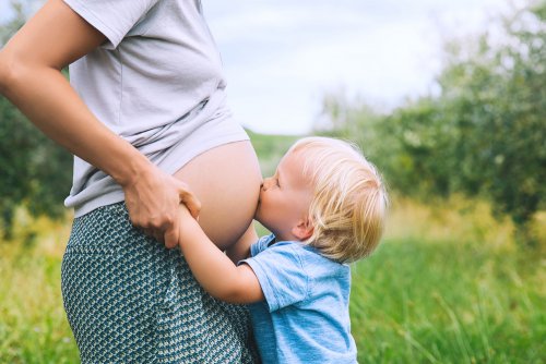 Niño abrazando y besando la barriga de su mamá embarazada.