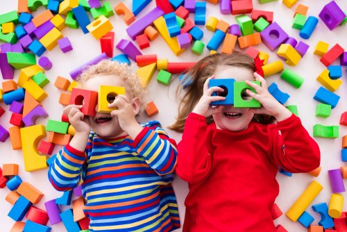 Deux enfants qui jouent avec des formes et cubes colorés.