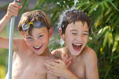 Niños jugando con una manguera de agua para divertirse en verano.