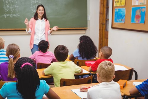 Profesora en clase explicando a sus alumnos qué es la autoevaluación para su educación.