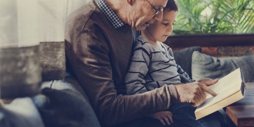 Abuelo leyendo libros infantiles informativos a su nieto.