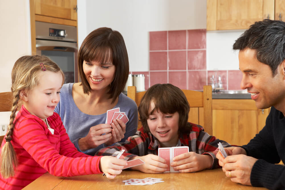 Familia jugando a las cartas sin dejar ganar a su hijos.
