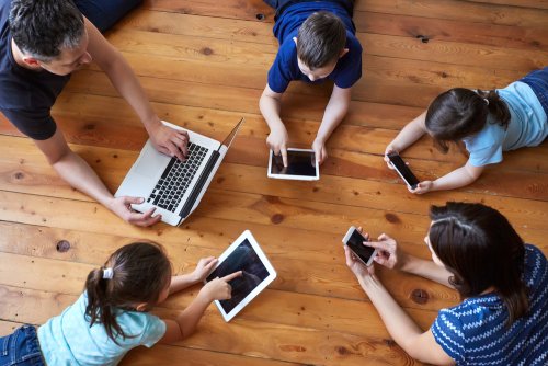 Familia jugando con ordenador, móviles y tablets.