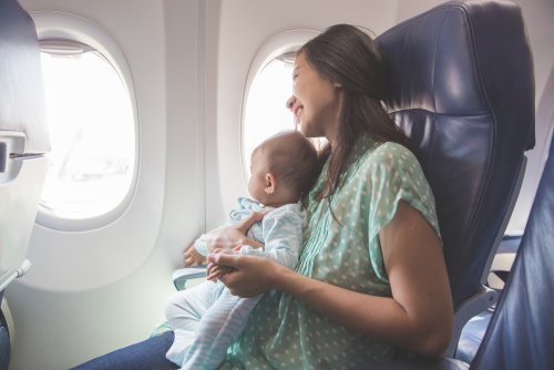 Mamá con su bebé en brazos en el asiento del avión.