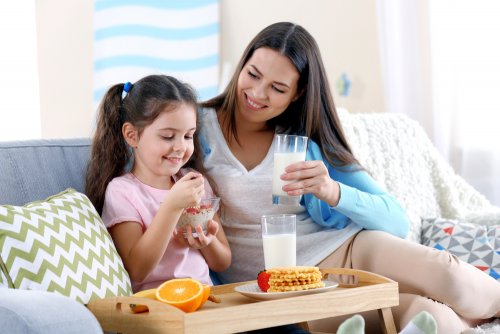 Madre e hija merendando fruta y algunos productos lácteos.