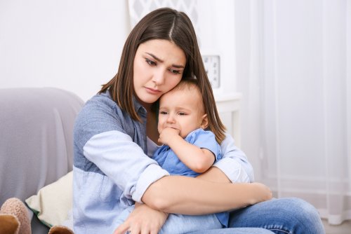 Madre con su bebé en brazos muy pensativa.