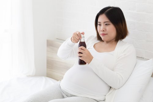 Mujer embarazada bebiendo un refresco de cola con cafeína.