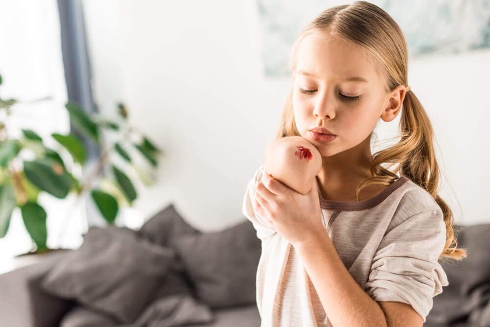 A young girl blowing on her skinned elbow.