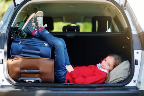 Niña metida en el maletero del coche antes de partir hacia su viaje al extranjero.