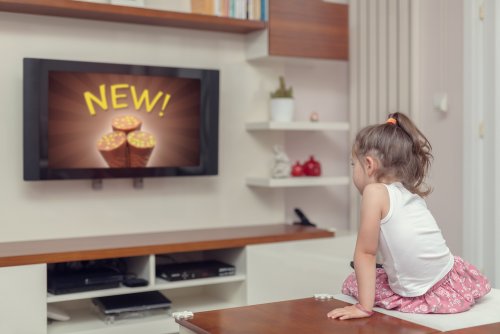 Niña viendo en la televisión anuncios publicitarios.