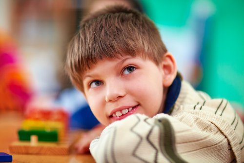 Niño con necesidades especiales sonriendo en el aula.