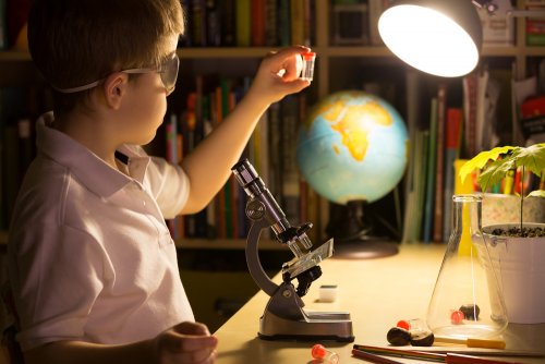 Niño muy curioso aprendiendo en su casa con el telescopio.