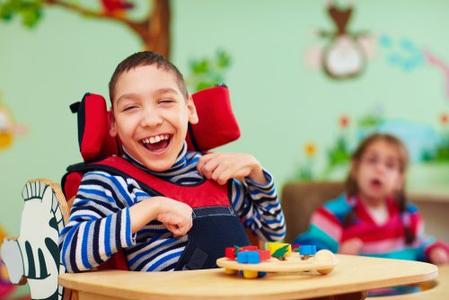 Bambino con disabilità motoria in classe molto sorridente.