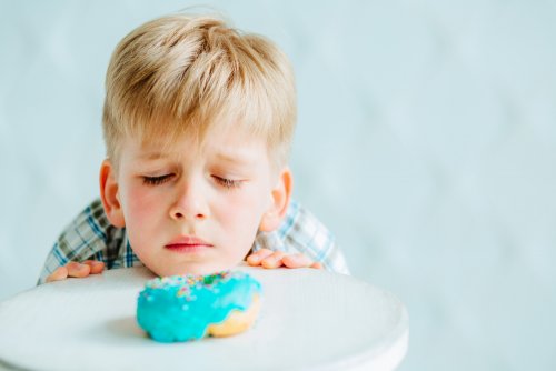 Niño mirando con pena un donut porque no puede comerlo debido a su intolerancia al gluten.