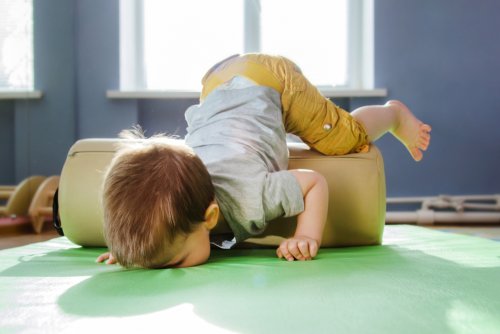 Niño jugando en la colchoneta en sala de psicomotricidad.