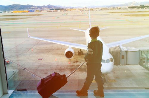 Niño mirando por la ventana del aeropuerto los vuelos que llegan.