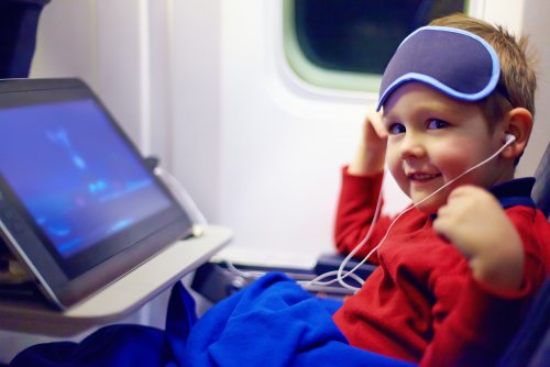 Niño viendo una película en el avión durante su vuelo para ir de vacaciones.
