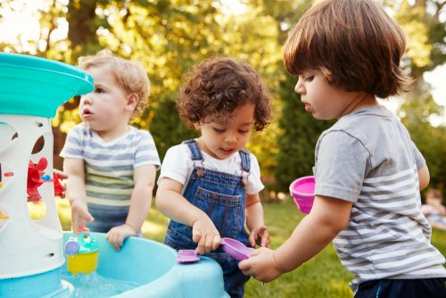 Niños jugando al aire libre con agua y formando parte de un experimento.