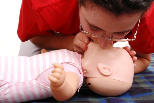 Persona haciendo la rcp a un maniquí bebé para aprender el soporte vital básico.