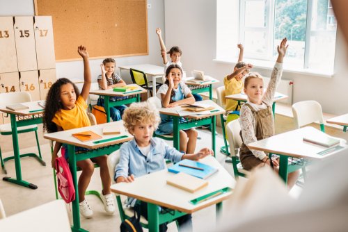Alumnado levantando las manos con muy buena participación en la escuela.