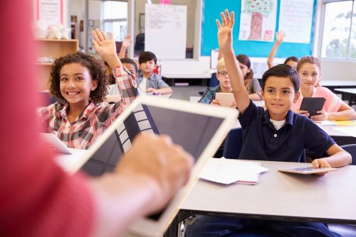 Alumnos con la mano levantada en una de las escuelas del siglo XXI.