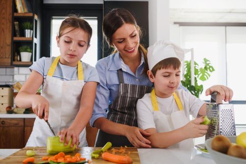 Madre cocinando con sus hijos para enseñarles la disciplina en la alimentación saludable.
