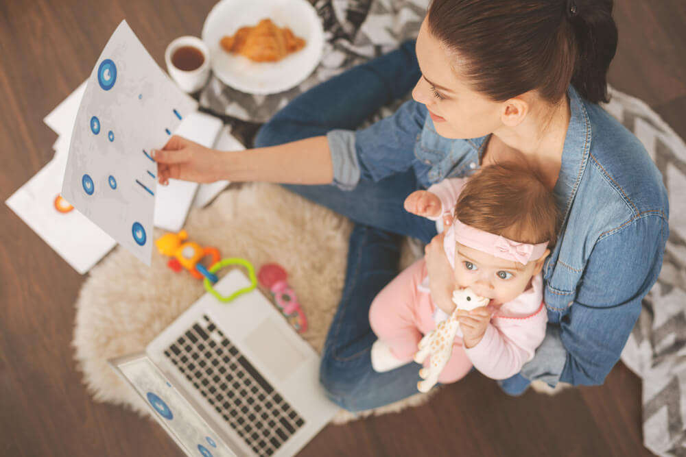 Mamá todoterreno haciendo mil tareas a la vez con su bebé en brazos.