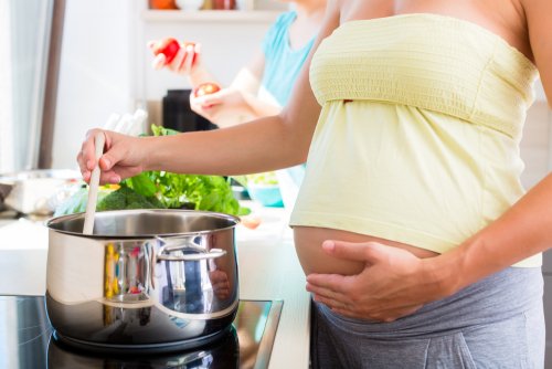 Mujer embarazada siguiendo los consejos de seguridad alimentaria en embarazadas mientras cocina.