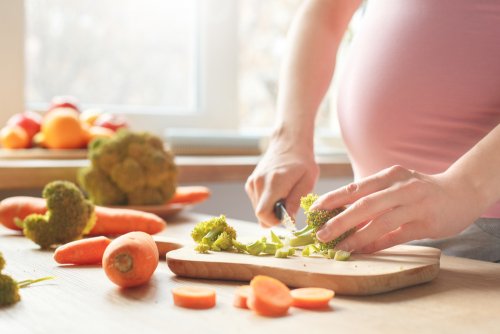 Mujer cocinando alimentos con nutrientes básicos para tener un buen embarazo.