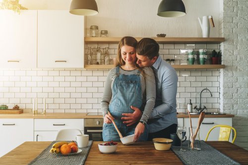 Mujer embarazada cocinando junto a su pareja.