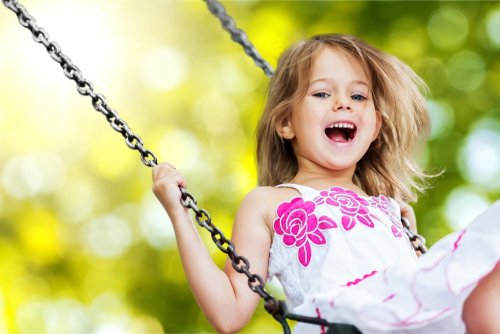 A happy girl swining on a swing.