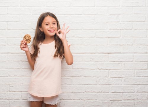 Niña recibiendo una galleta a modo de refuerzo positivo por su buen comportamiento y las pegatinas recibidas en el sistema de economía de fichas.