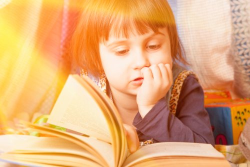 Niña leyendo uno de los libros infantiles informativos que proponemos en este artículo.