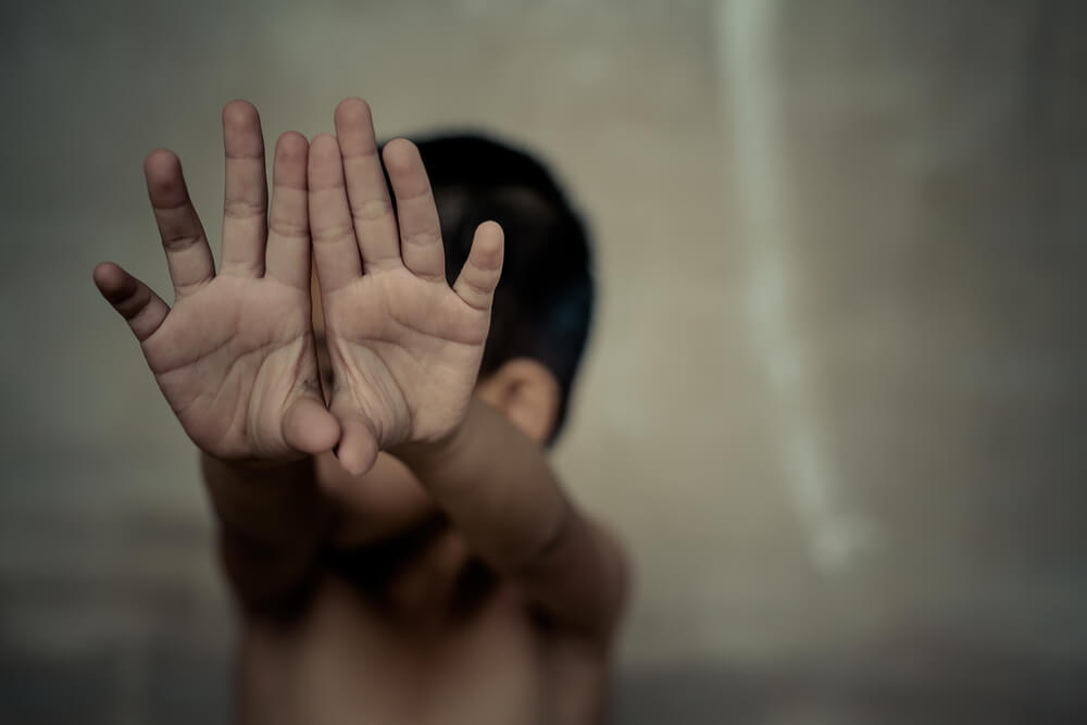 Bambino con le mani alzate vittima di abusi sui minori.
