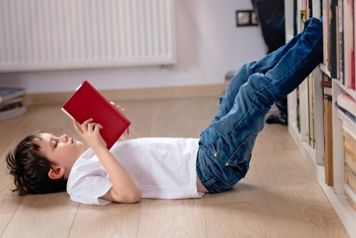Niño leyendo un libro de Isadora Moon tumbado en el suelo.