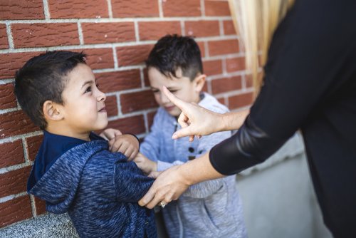 Profesora parando a un alumno que le estaba haciendo bullying a otro en el patio del colegio.