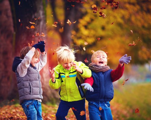 Trois enfants qui jouent avec les feuilles de l'automne.