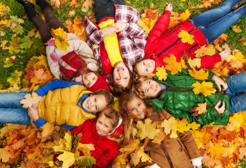 Niños tumbados sobre las hojas caídas del otoño.